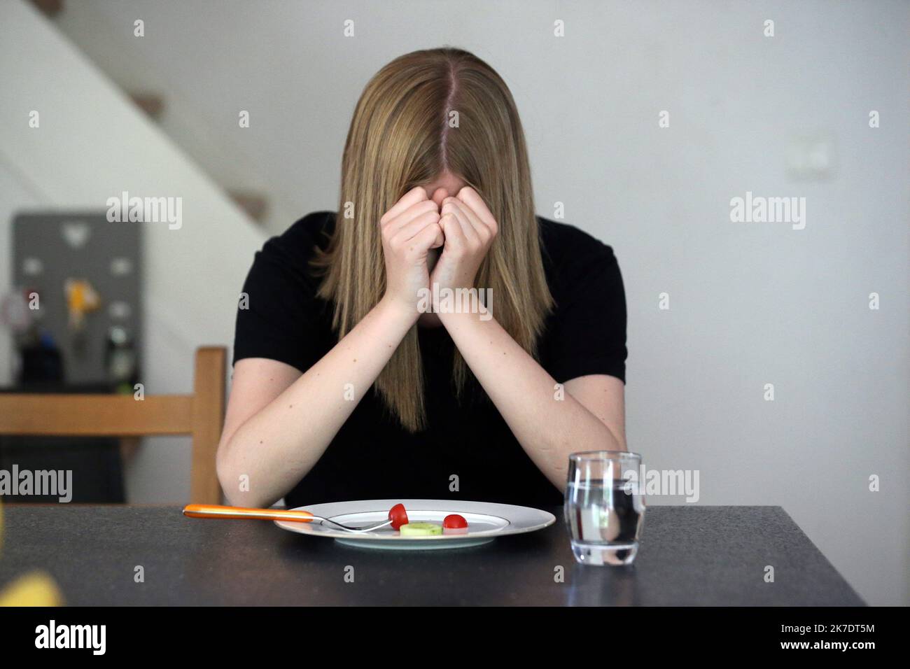 ©PHOTOPQR/L'ALSACE/Vanessa MEYER ; ; 02/06/2021 ; Une jeune fille tient sa tête entre ses mains devant une assiette presque vide avec une tomate cerise et une rondelle de concombre. Les troubles du comportement alimentaire ont augmenté pendant la crise sanitaire. - anorexia Stock Photo