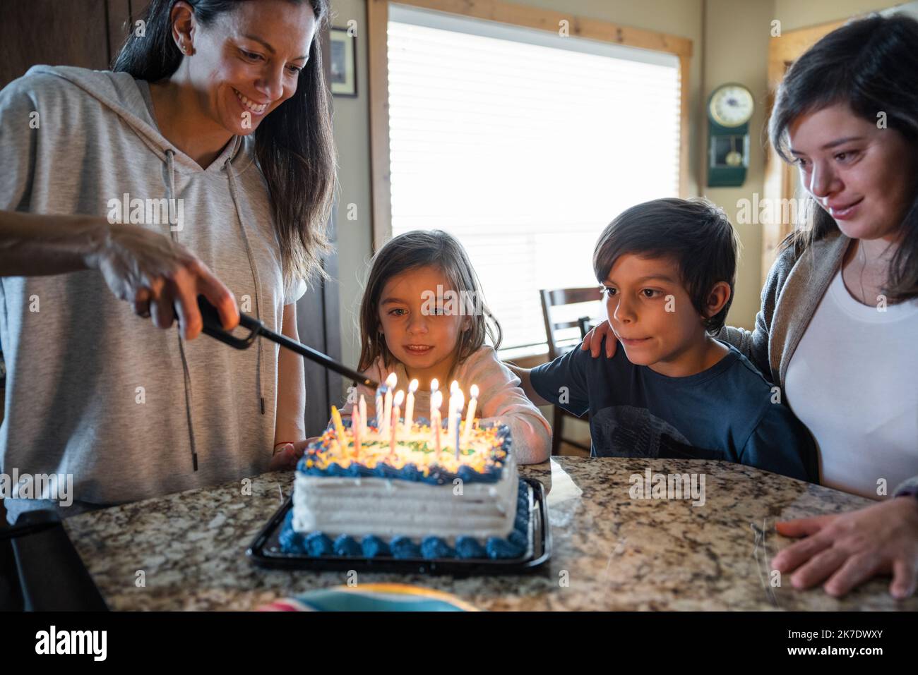Mother lighting up candles on birthday cake at home Stock Photo Alamy