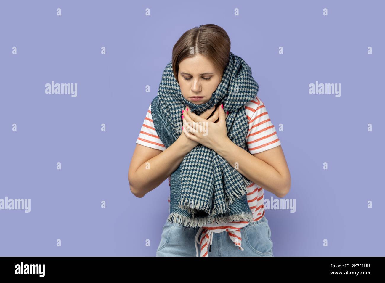 Portrait of sick unhealthy blond woman wearing striped Tshirt and wrapped in scarf suffering