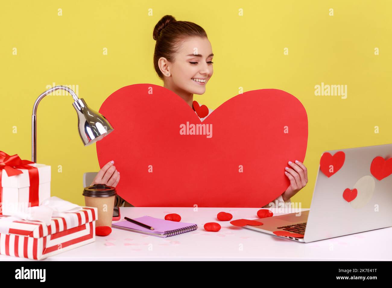 Happy woman holding big red paper heart and smiling, sitting at ...