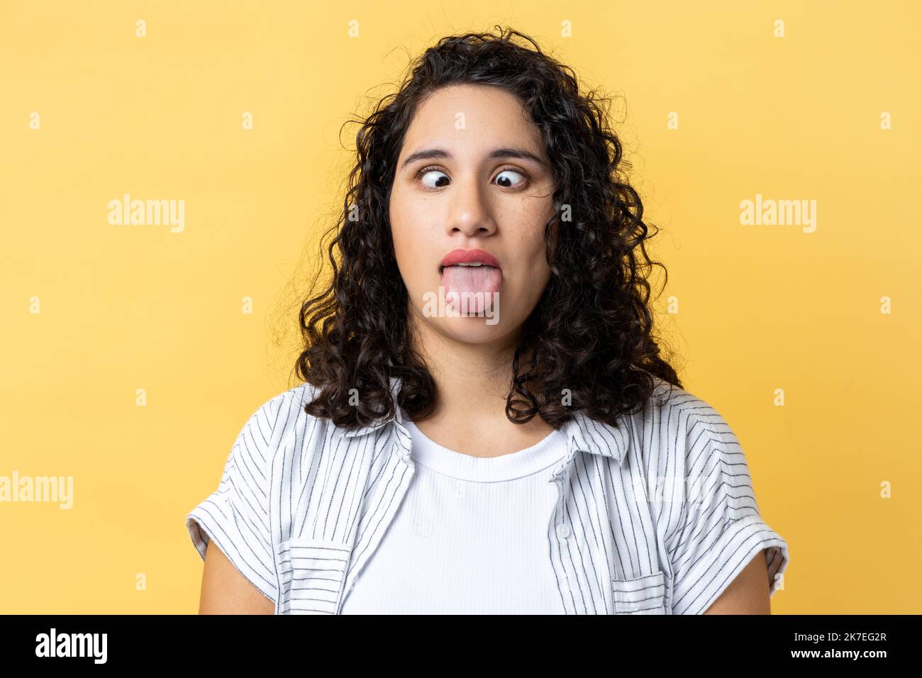 Portrait of woman with dark wavy hair standing with crossed eyes and