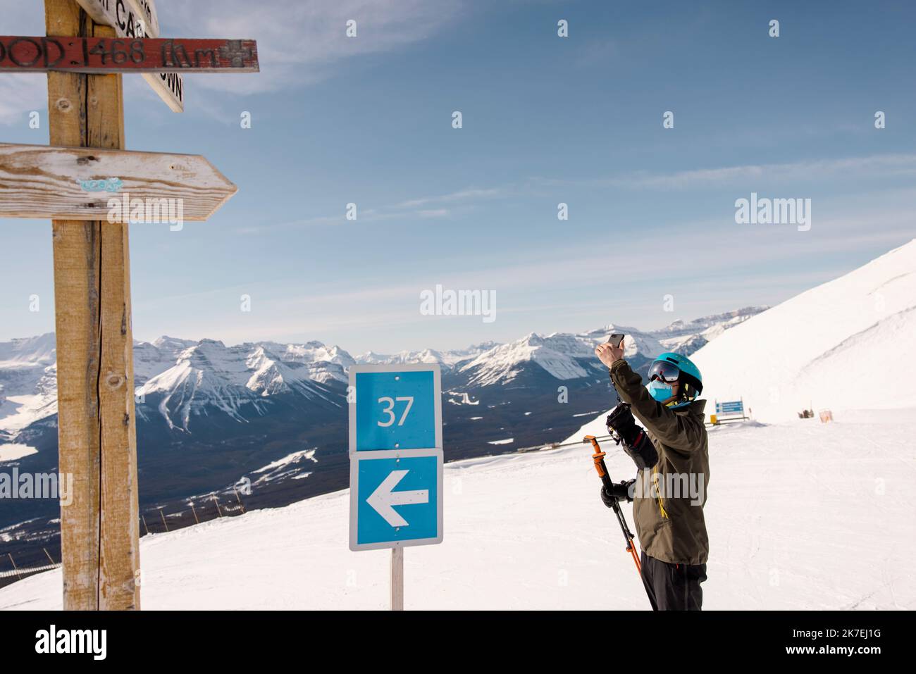 Skier using smart phone on sunny mountain ski resort slope Stock Photo