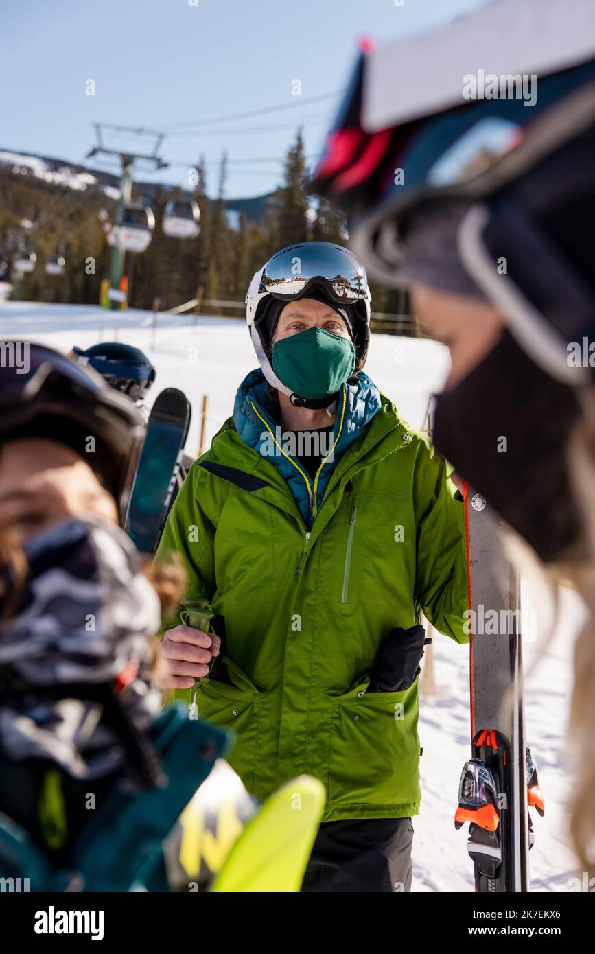 Family in face masks with skis at sunny ski resort Stock Photo Alamy