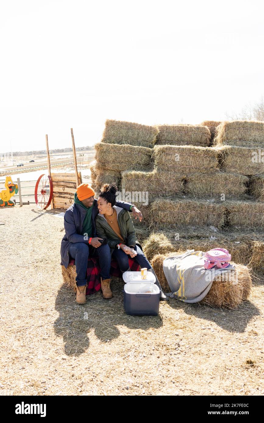 Happy couple enjoying lunch at hay bales on sunny farm Stock Photo - Alamy