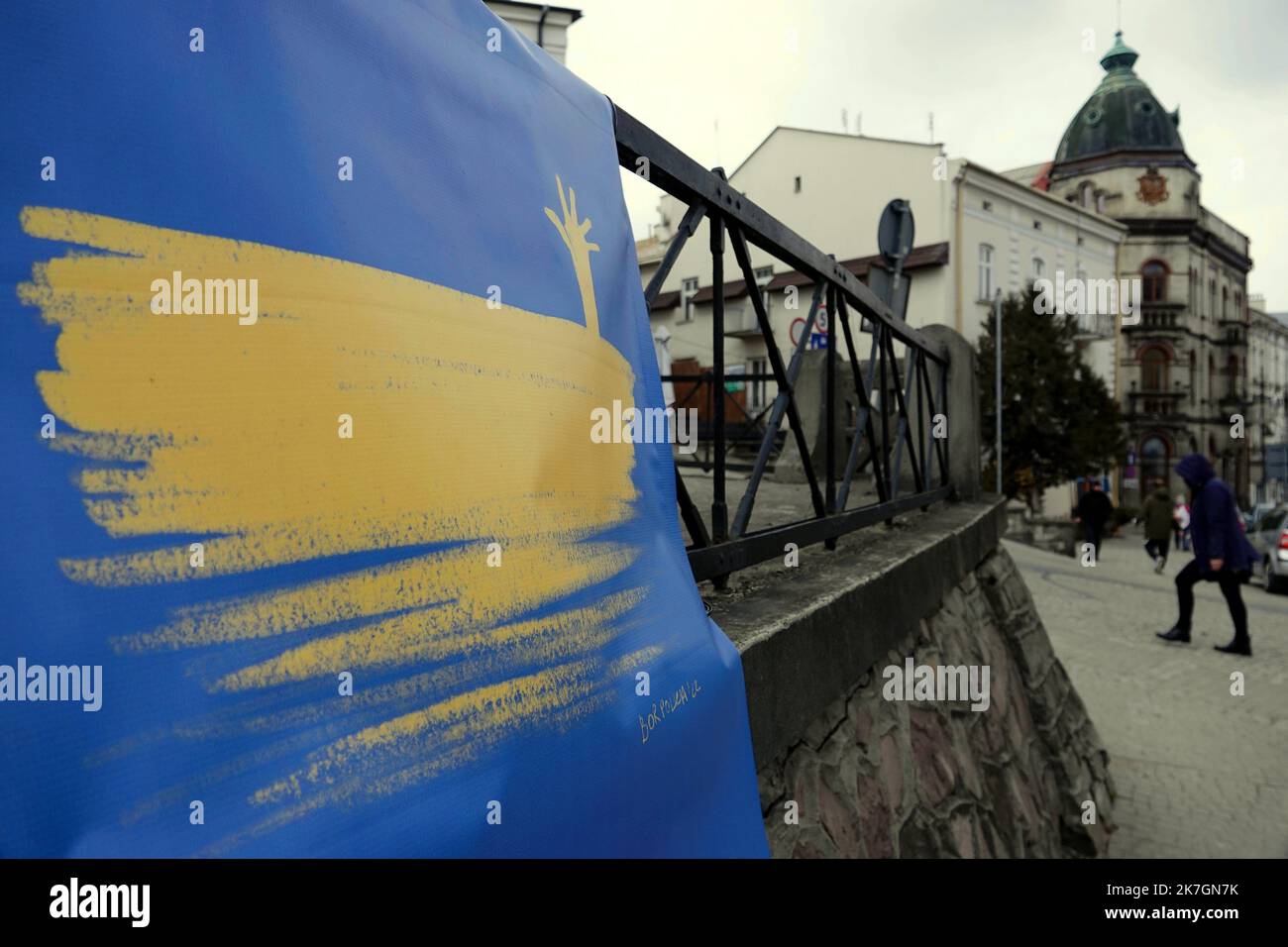 ©PHOTOPQR/L'EST REPUBLICAIN/Alexandre MARCHI ; PRZEMYSL ; 10/03/2022 ; GUERRE EN UKRAINE - CONFLIT AVEC LA RUSSIE - POLOGNE - POUTINE - PUTIN - BLOOD. Prezmsyl 10 mars 2022. Une personne passe devant une bâche représentant le drapeau urainien sur une place du centre ville de Przemysl à quelques kilomètres de frontière ukrainienne. PHOTO Alexandre MARCHI. war in ukraine Prezmsyl on Mar 10, 2022  Stock Photo