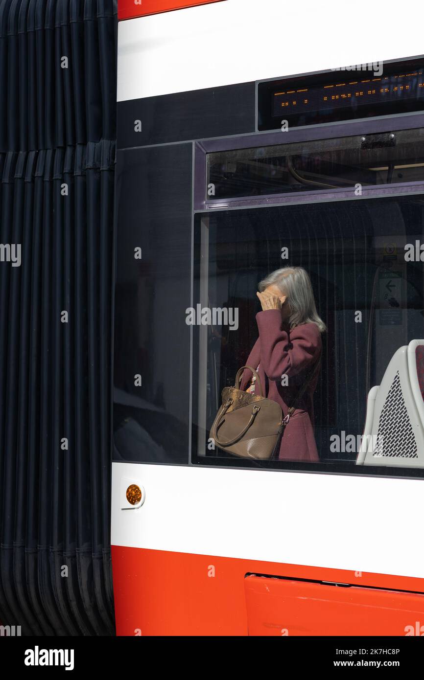 Older woman shielding her eyes from the sun on a streetcar, Toronto, Ontario, Canada. Stock Photo