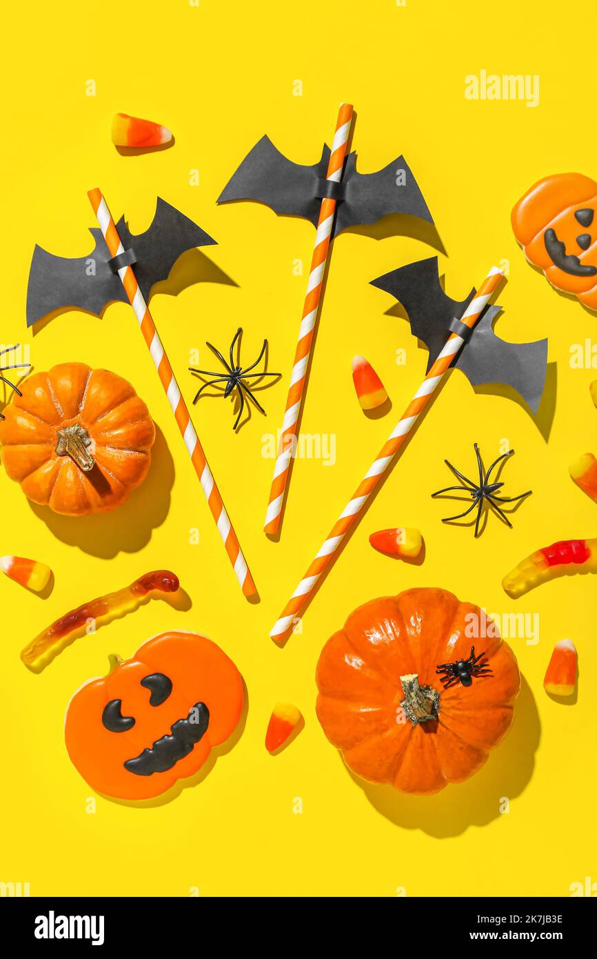 Paper bats with straws and Halloween treats on yellow background Stock ...