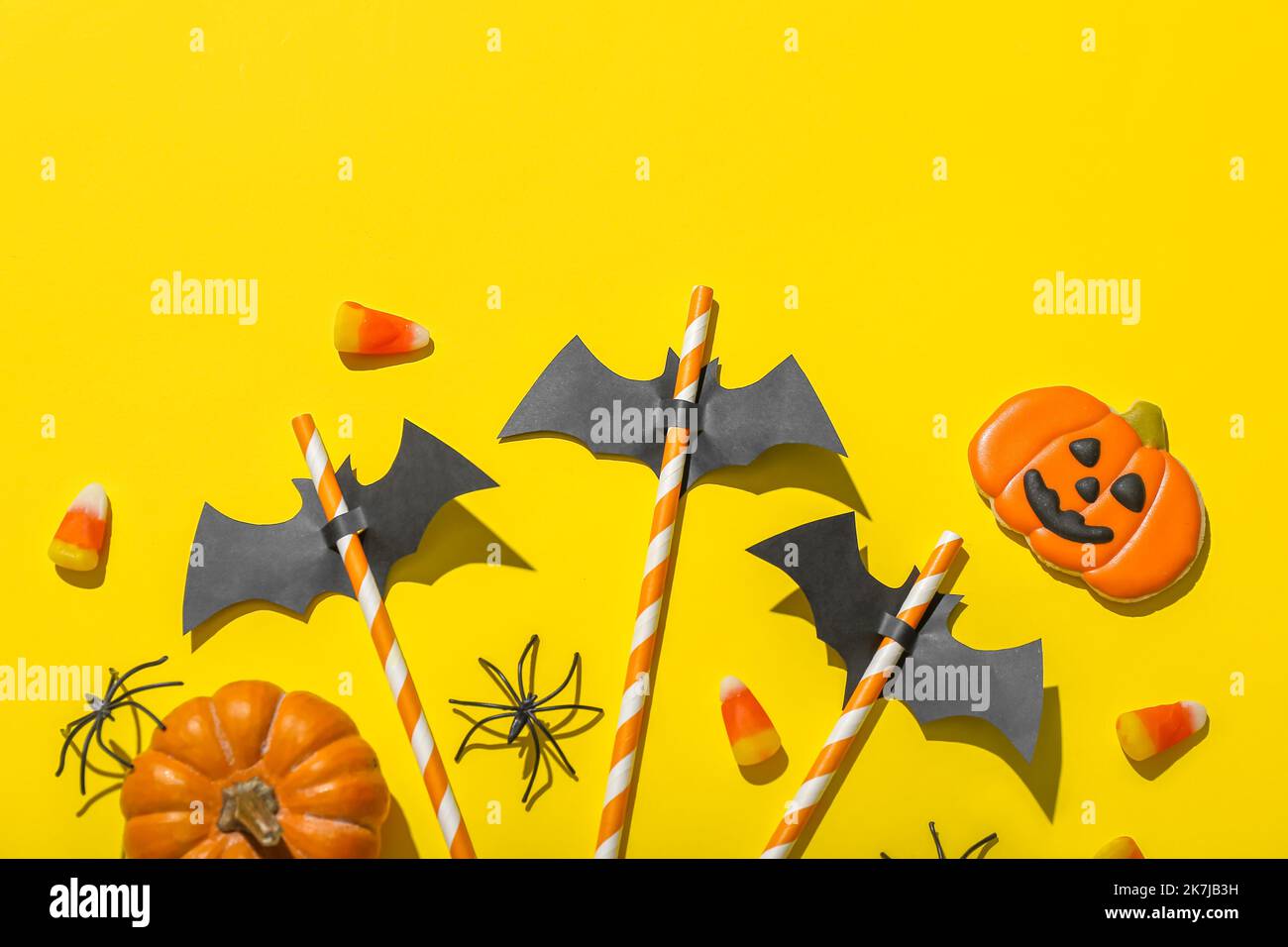 Paper bats with straws and Halloween treats on yellow background Stock ...