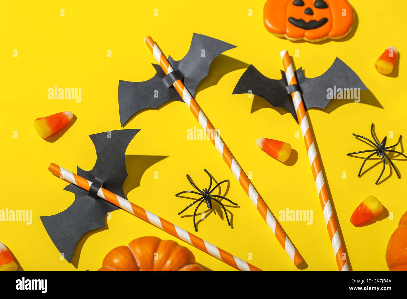 Paper bats with straws and Halloween treats on yellow background Stock ...