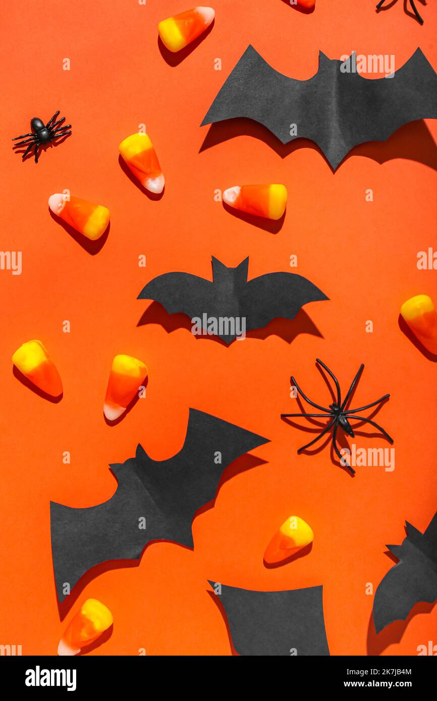 Paper bats with candy corns and spiders on red background Stock Photo ...