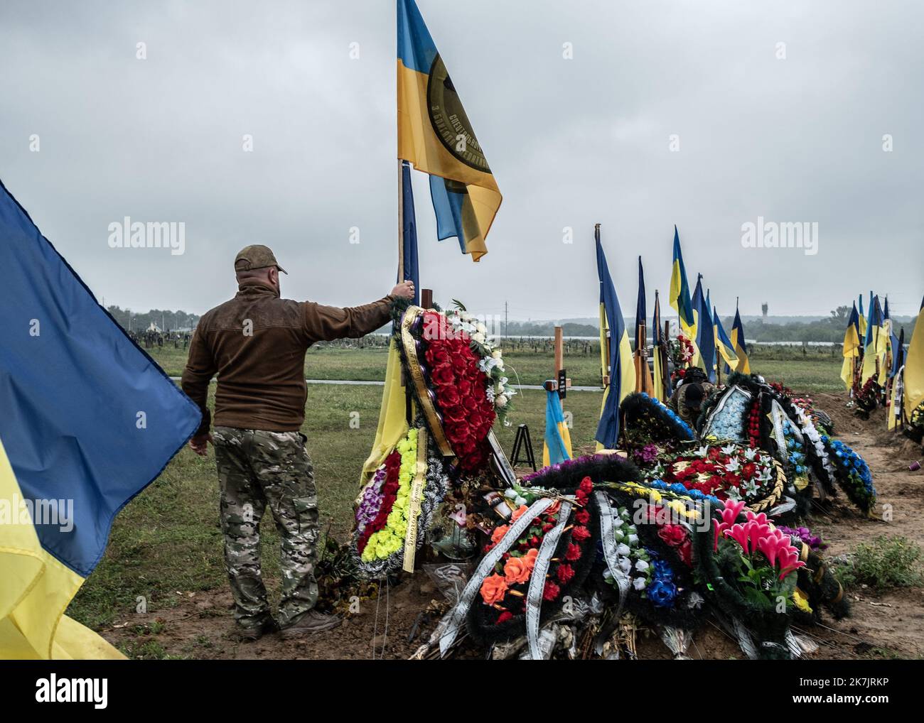 ©Sadak Souici / Le Pictorium/MAXPPP - Kharkiv 16/07/2022 Sadak Souici / Le Pictorium - 16/7/2022 - Ukraine / Kharkov / Kharkiv - Un soldat ukrainien tient le drapeau de son bataillon sur la tombe de son camarade mort sur la ligne de front a Kharkiv. Le cimetiere N°18 de Kharkiv a Bezlioudivka qui comprend une section militaire datant d'il y a plusieurs annees, accueille les depouilles des soldats morts depuis le debut de la guerre contre la Russie. Samedi, plusieurs enterrements de soldats y ont eu lieu. / 16/7/2022 - Ukraine / Kharkov / Kharkiv - A Ukrainian soldier holds the flag of his batt Stock Photo