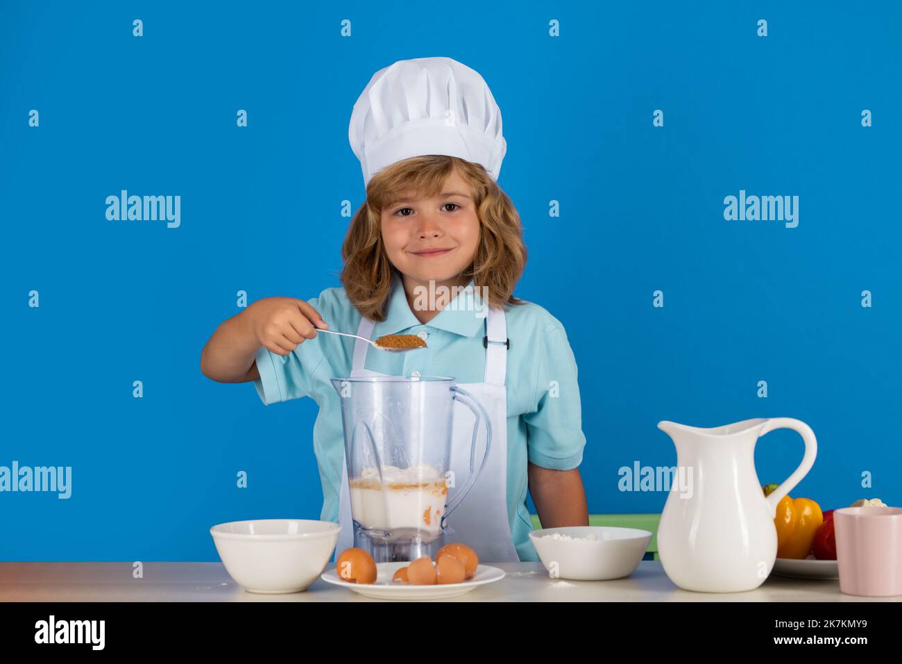 Portrait of a 7, 8 years old child in cook cap and apron making fruit