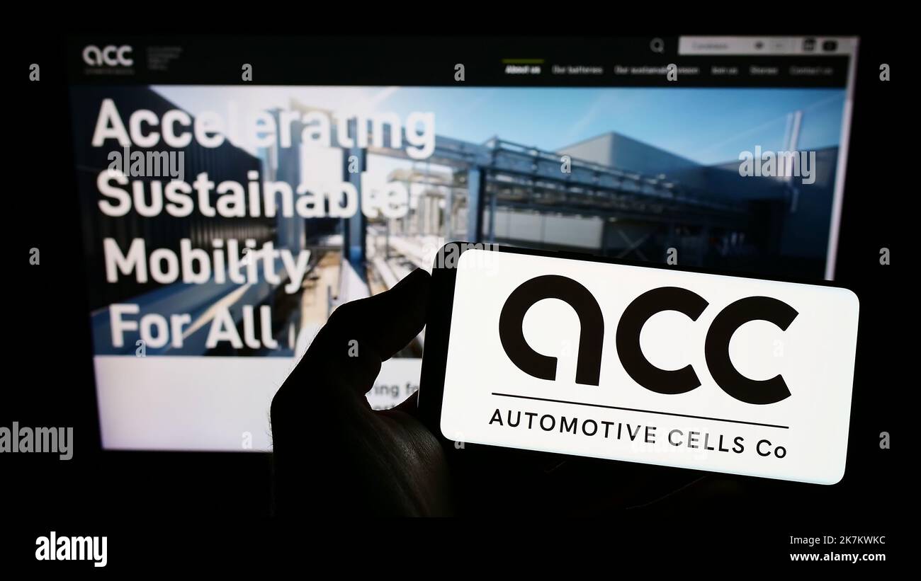 Person holding smartphone with logo of French Automotive Cells Company SE (ACC) on screen in front of website. Focus on phone display. Stock Photo