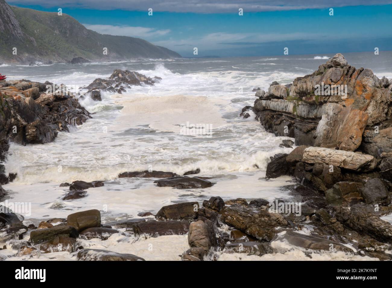 Tides in at Storms River with tide in and massive breakers crashing on the rocky shoreline. Low shutter speed with leading lines and foamy surf Stock Photo