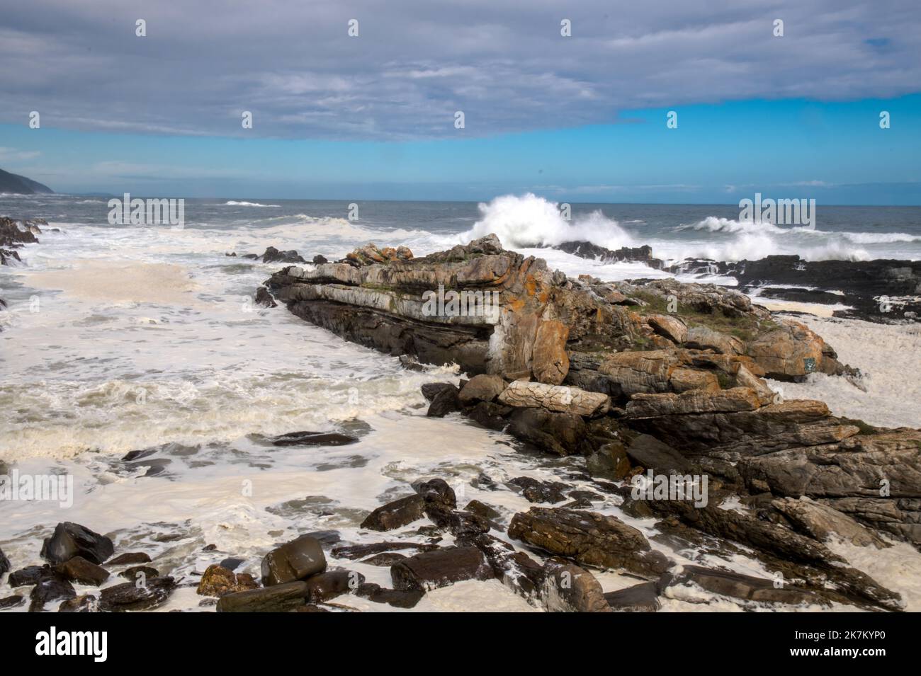 Tides in at Storms River with tide in and massive breakers crashing on the rocky shoreline. Low shutter speed with leading lines and foamy surf Stock Photo