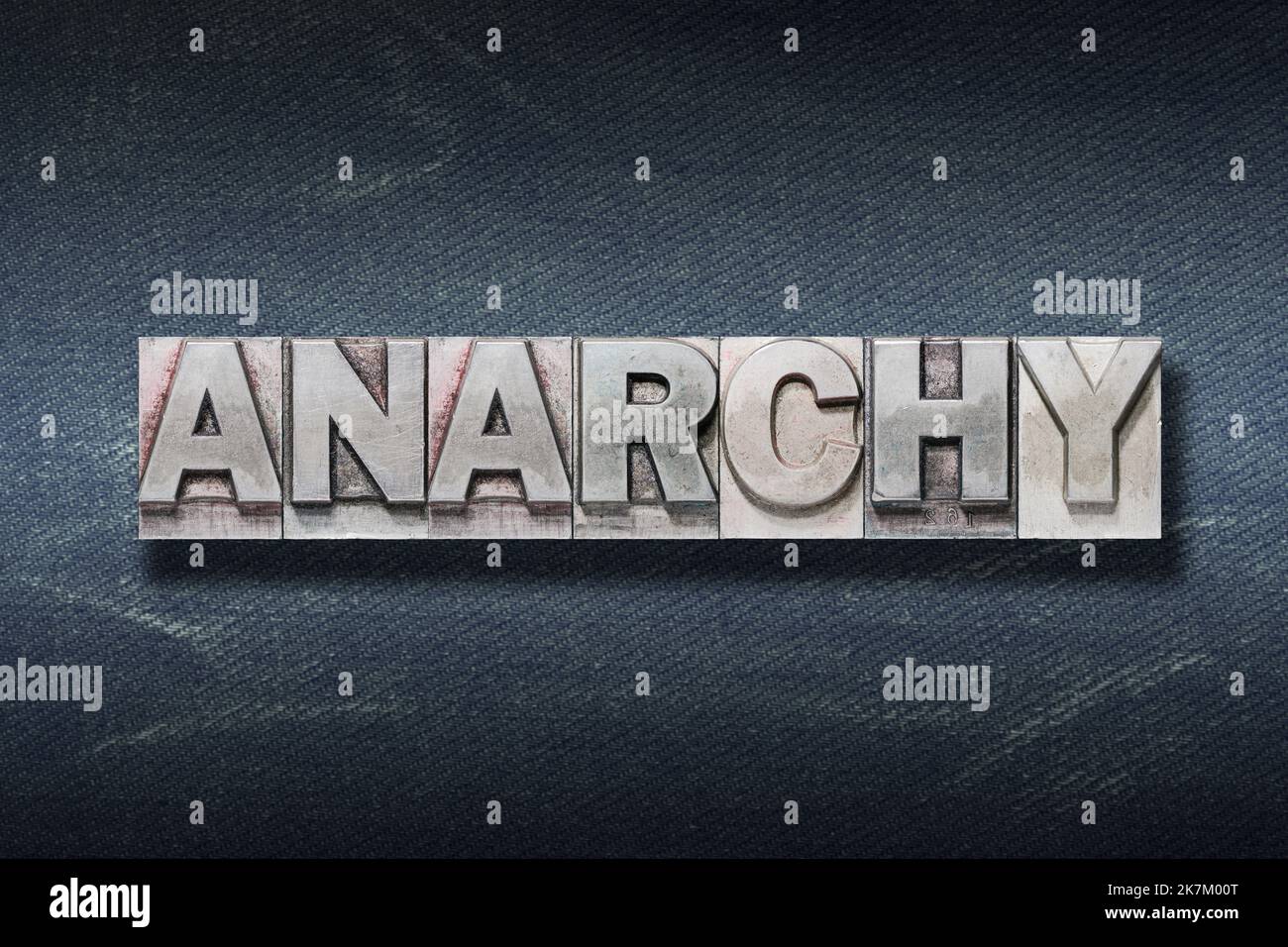 anarchy word made from metallic letterpress on dark jeans background Stock Photo