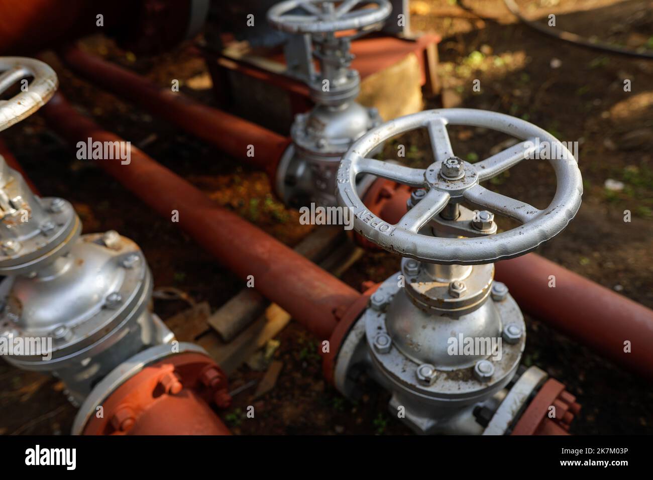 Shallow depth of field (selective focus) details with industrial metallic pipe valves used to open or close the hot water debit inside a big pipeline. Stock Photo