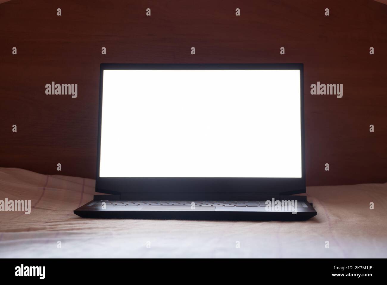 laptop with white screen stands on the bed in the bedroom at home