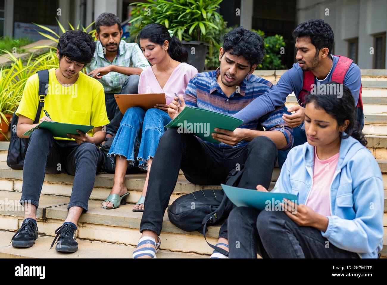 Group of students filling admission application form or preparing for exams on college campus by discussing eachother - concept of graduation, skill Stock Photo
