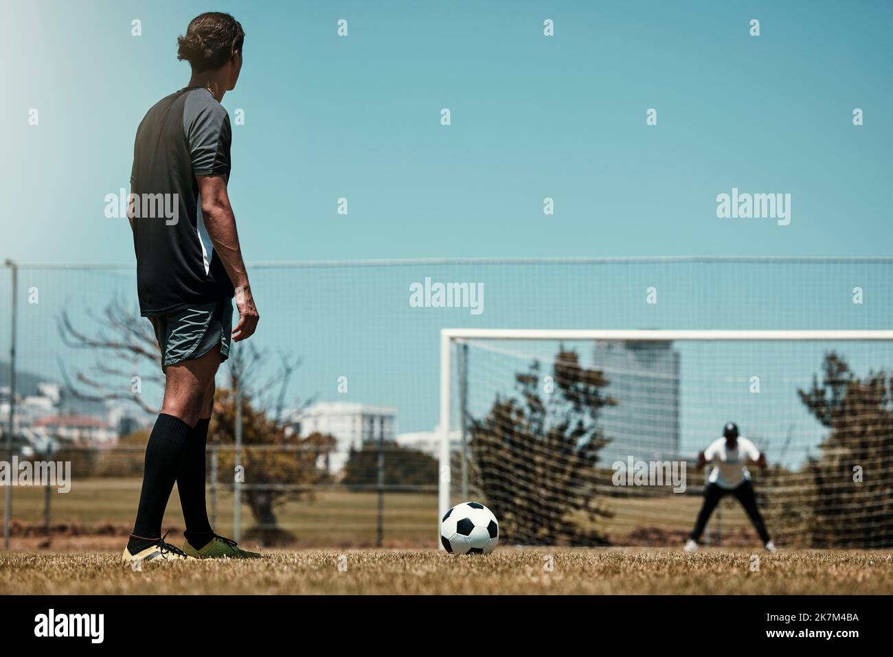 Training, goal and soccer player with goalkeeper at sports field for