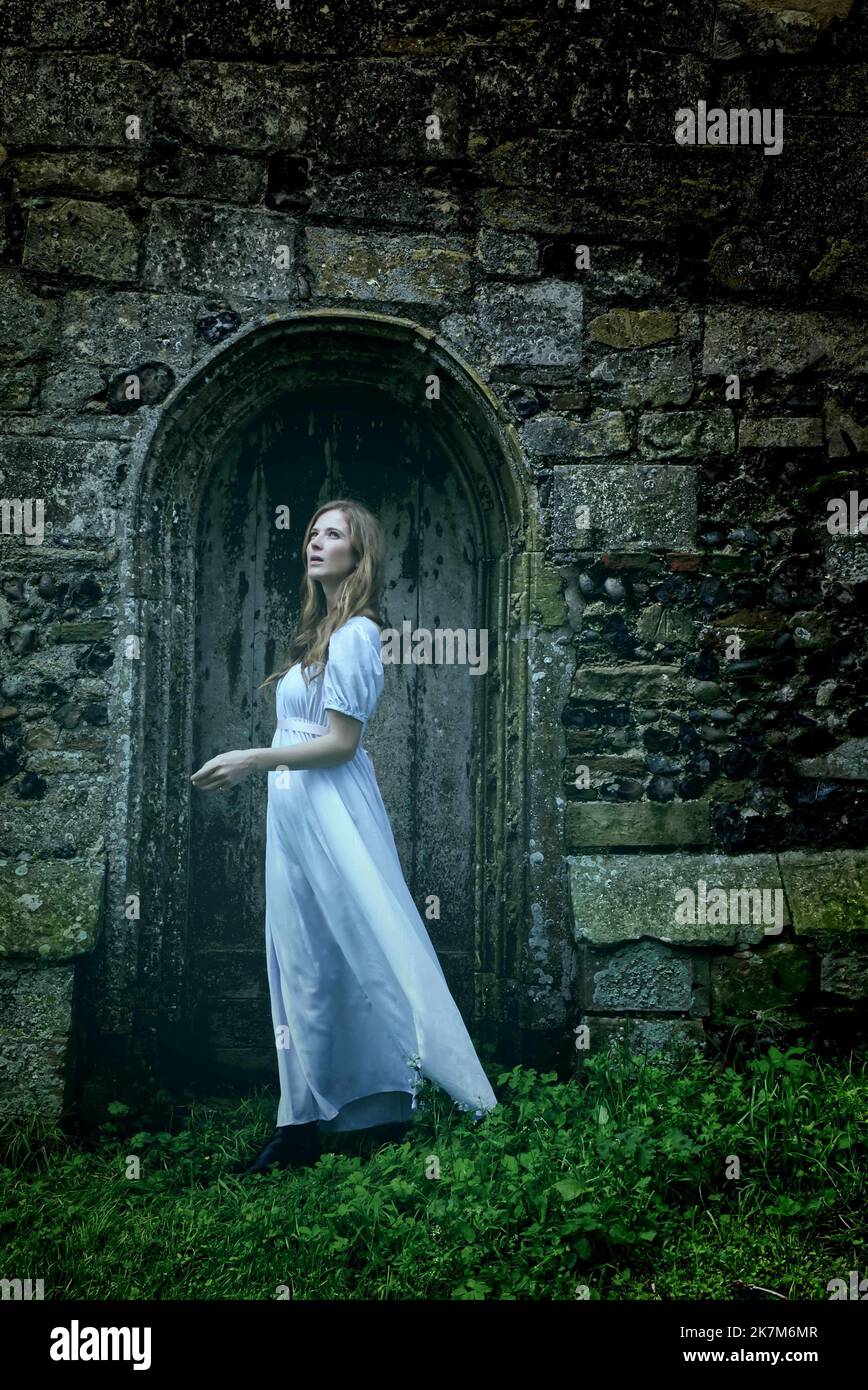 pale ghostly woman in front of old church door Stock Photo