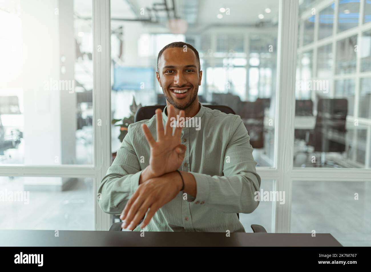 African businessman using sign language while talking online with client sitting in office Stock Photo