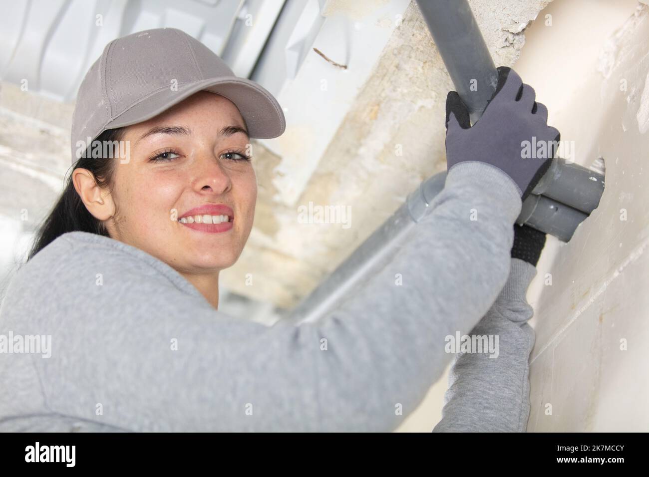 young woman looking at water leaking from sink pipe Stock Photo