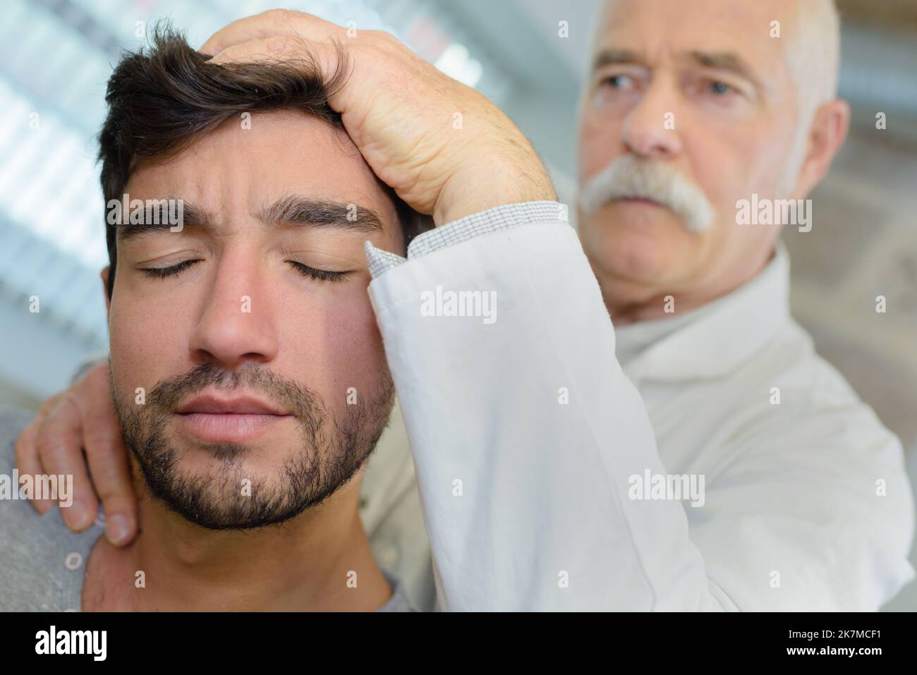 senior physiotherapist giving head massage to patient in clinic Stock Photo