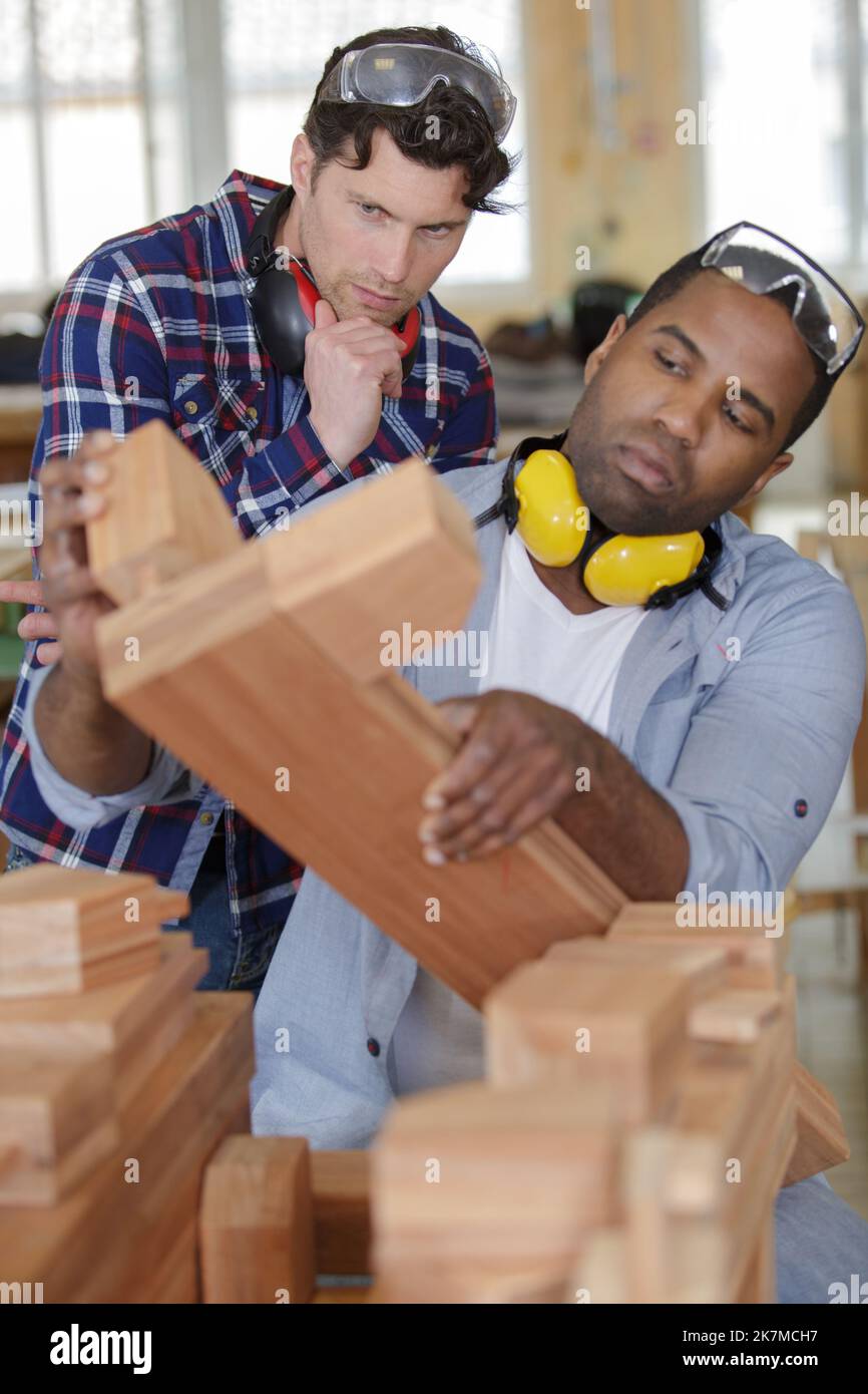 young carpenter with students in woodworking workshop Stock Photo
