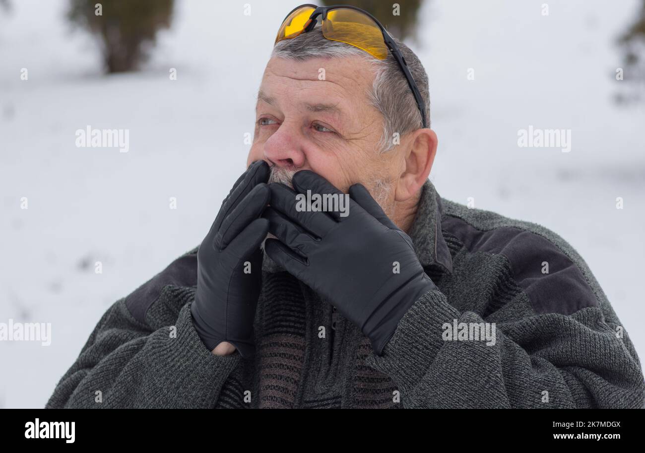 Portrait of Ukrainian senior man looking with surprise in winter park Stock Photo