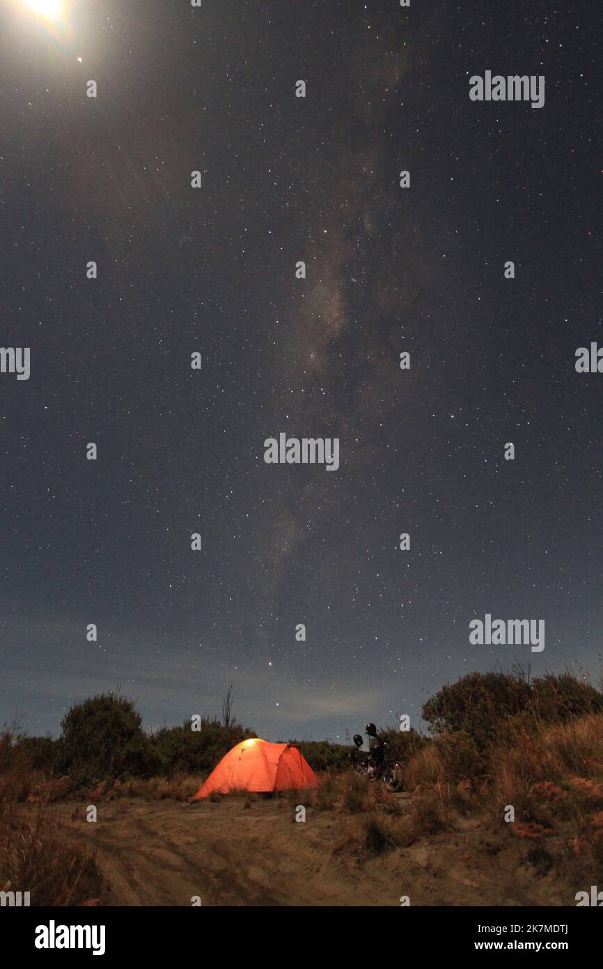 Tent and milkyway trail under the moonlight in Indonesia Stock Photo