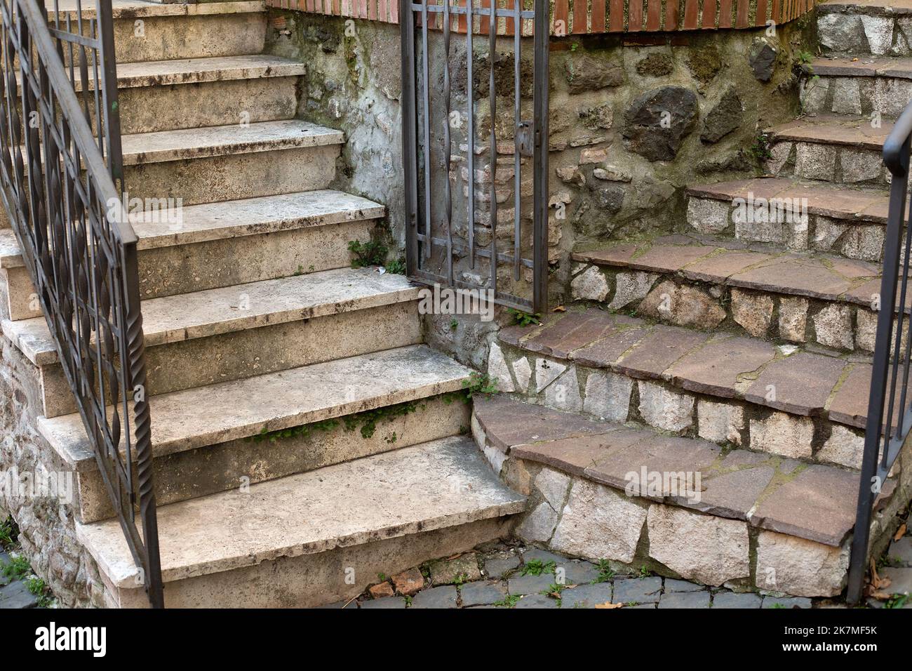 Two stone staircases with metal forged railing and a gate in the corner