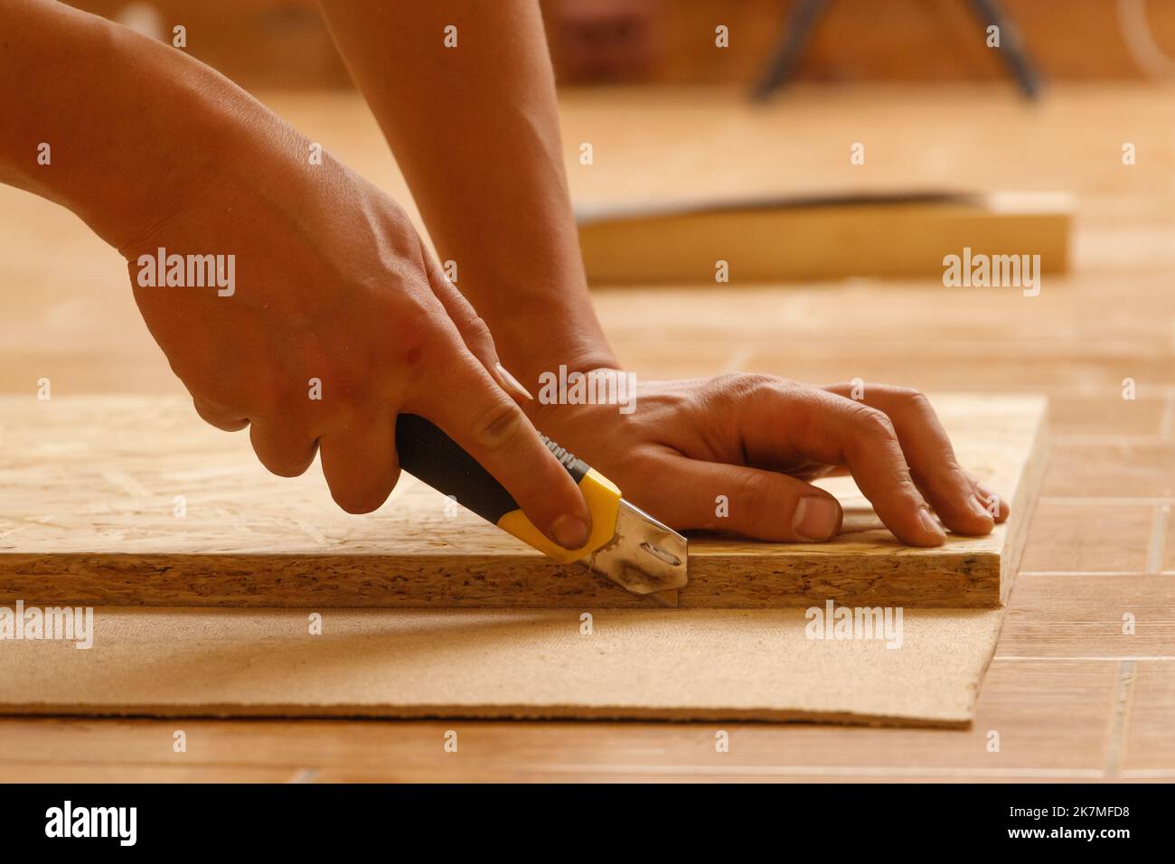 Side view of the hands of a Carpenter who cuts fiberboard while making furniture to order Stock Photo