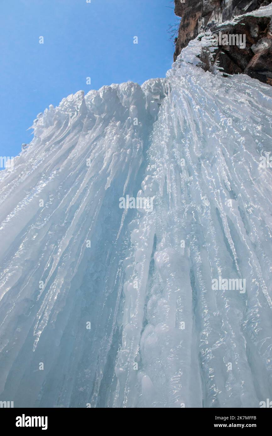 Bottom view of Frozen waterfall on rocky mountain in winter day Stock Photo