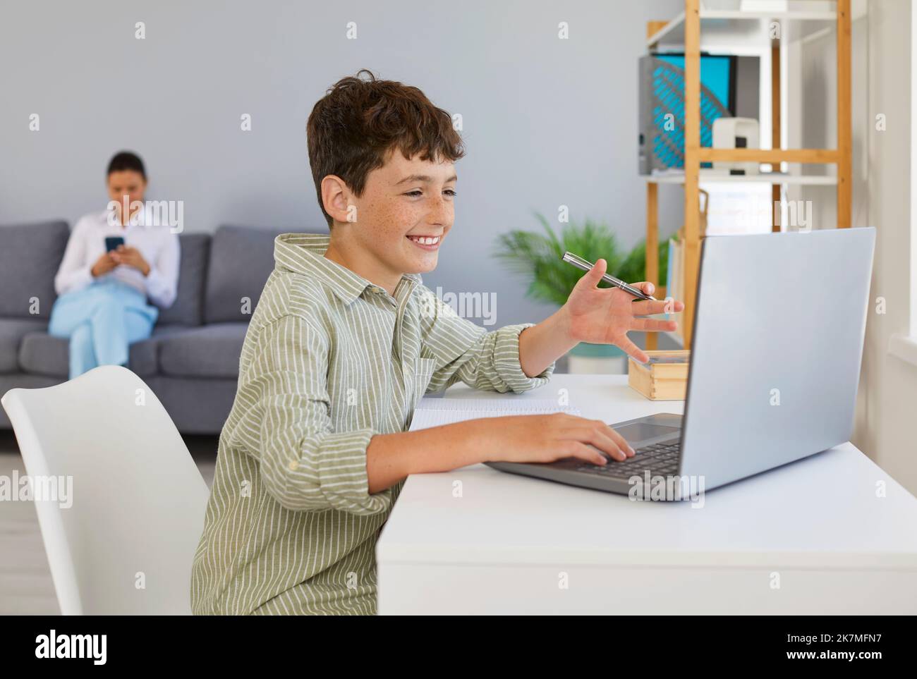 Happy school child having fun and using his laptop computer for online ...