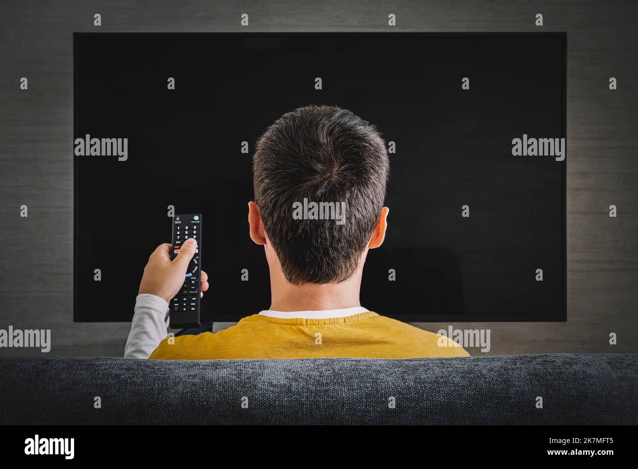 Man watching television, turning on plasma flatscreen TVset, pointing