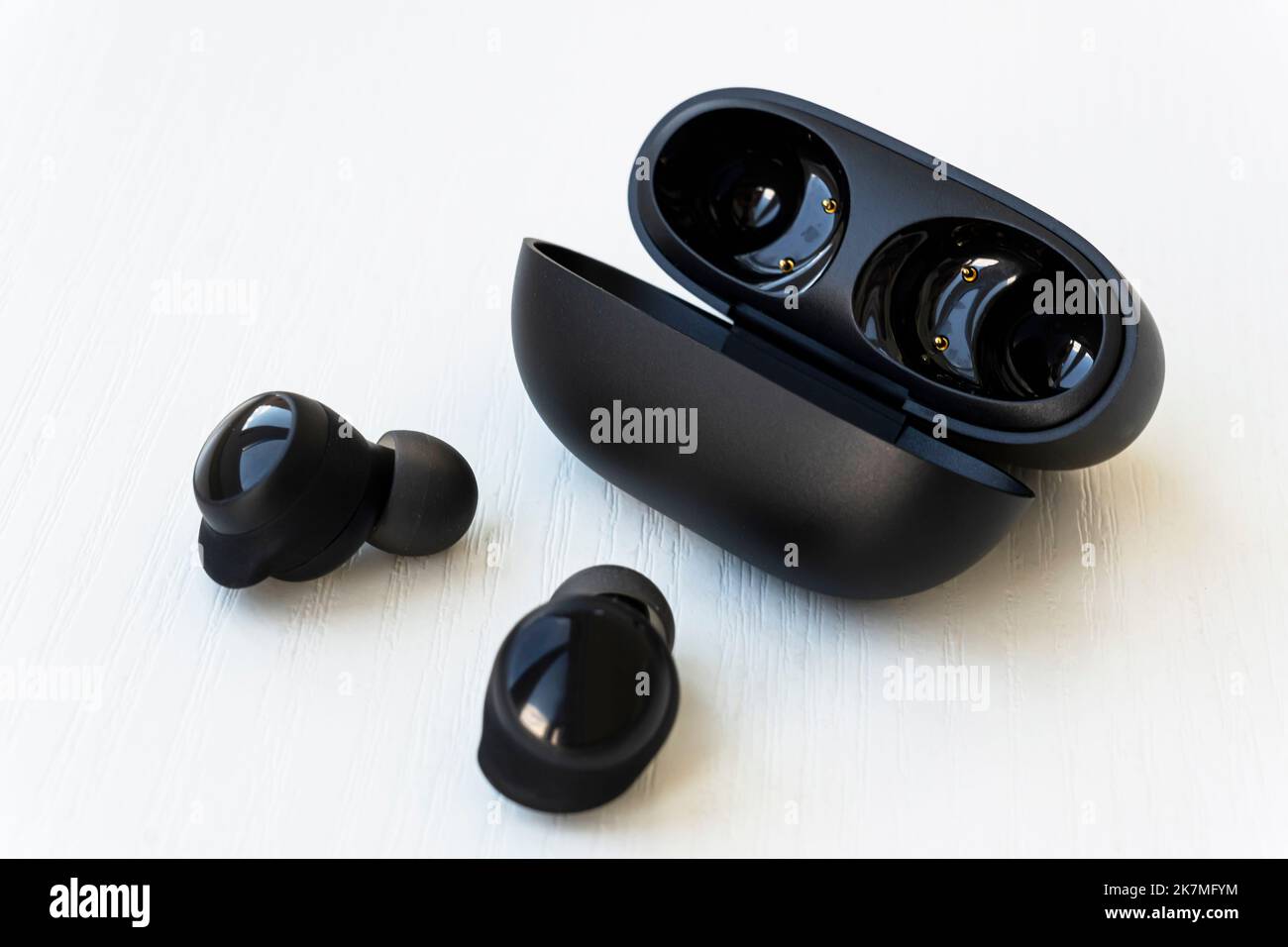 Wireless black earphones with contactless charging close-up on a white background. box with wireless headphones. Stock Photo