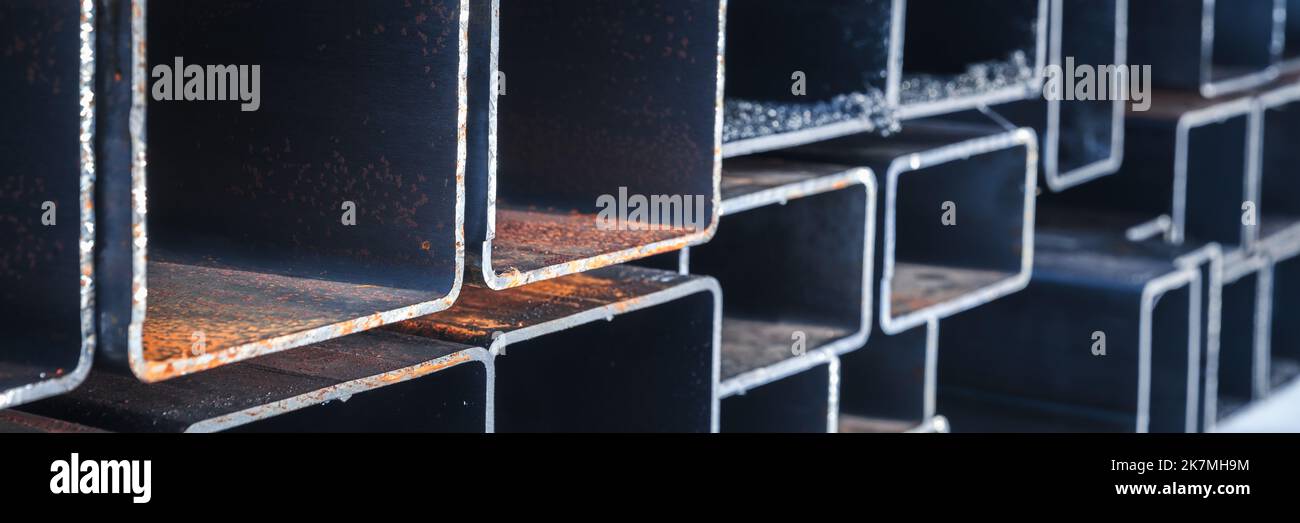 Abstract panoramic heavy industry background. Stack of rolled steel products, metal pipes with rectangular cross-section, close-up photo with selectiv Stock Photo