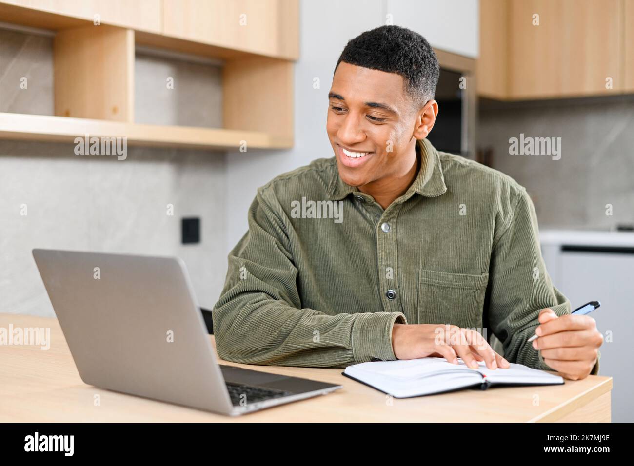 Concentrated latin student looking at the laptop display, solving business tasks, looking for new ideas while writing something at the notebook. People and technologies concept Stock Photo