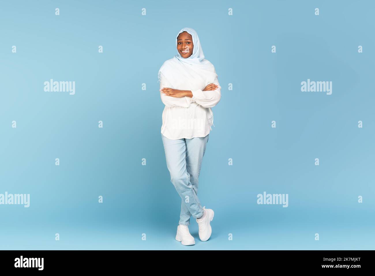 Happy african american woman in light hijab posing on blue studio background, full length shot, copy space Stock Photo