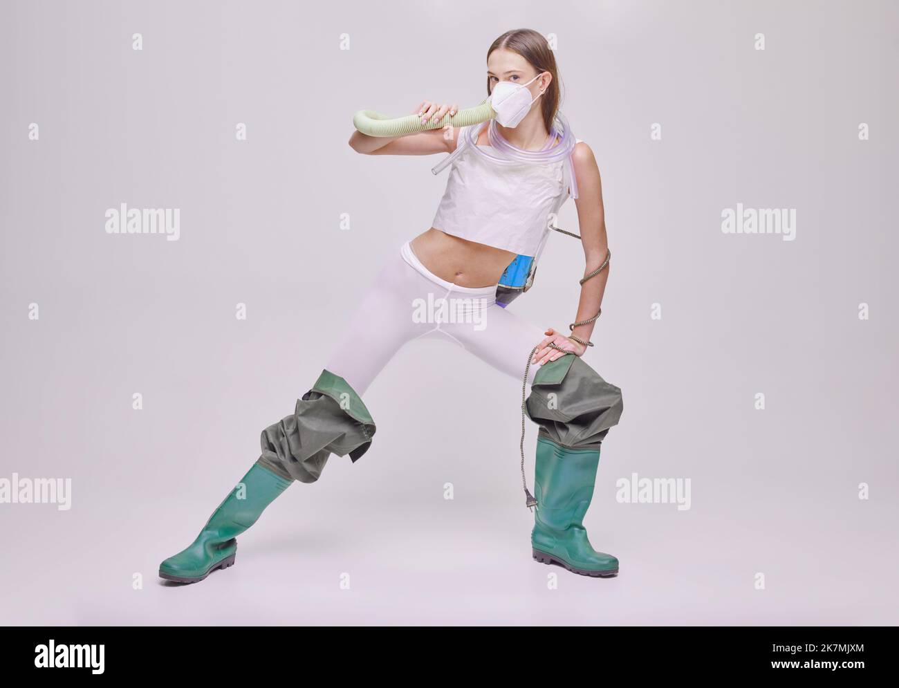 Portrait of girl posing in rubber boots, vacuum cleaner on back and
