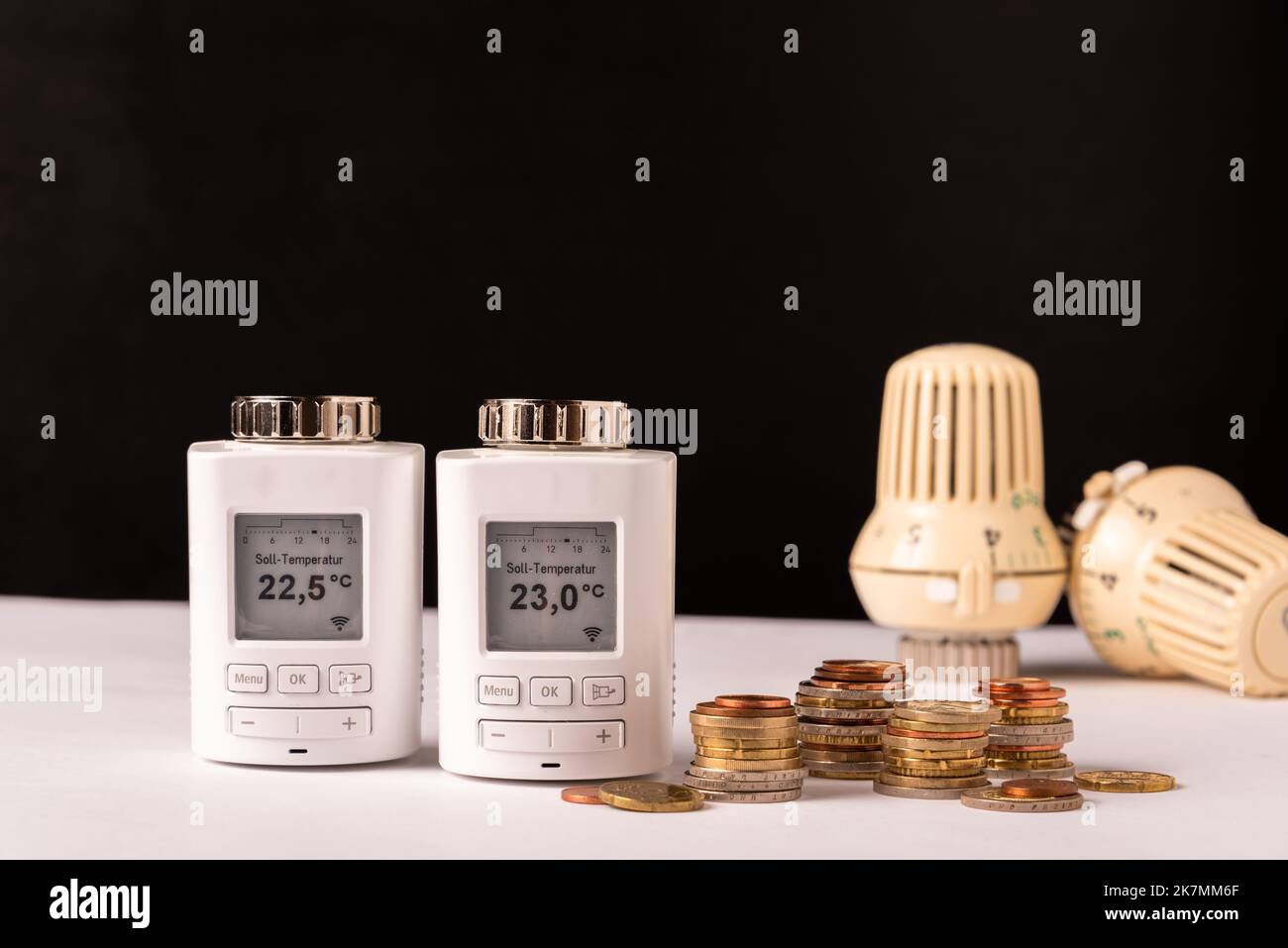 Elektronische Heizungsventile mit  Geldmünzen gegen manuelle Heizungsventile zur Kostensparung Stock Photo