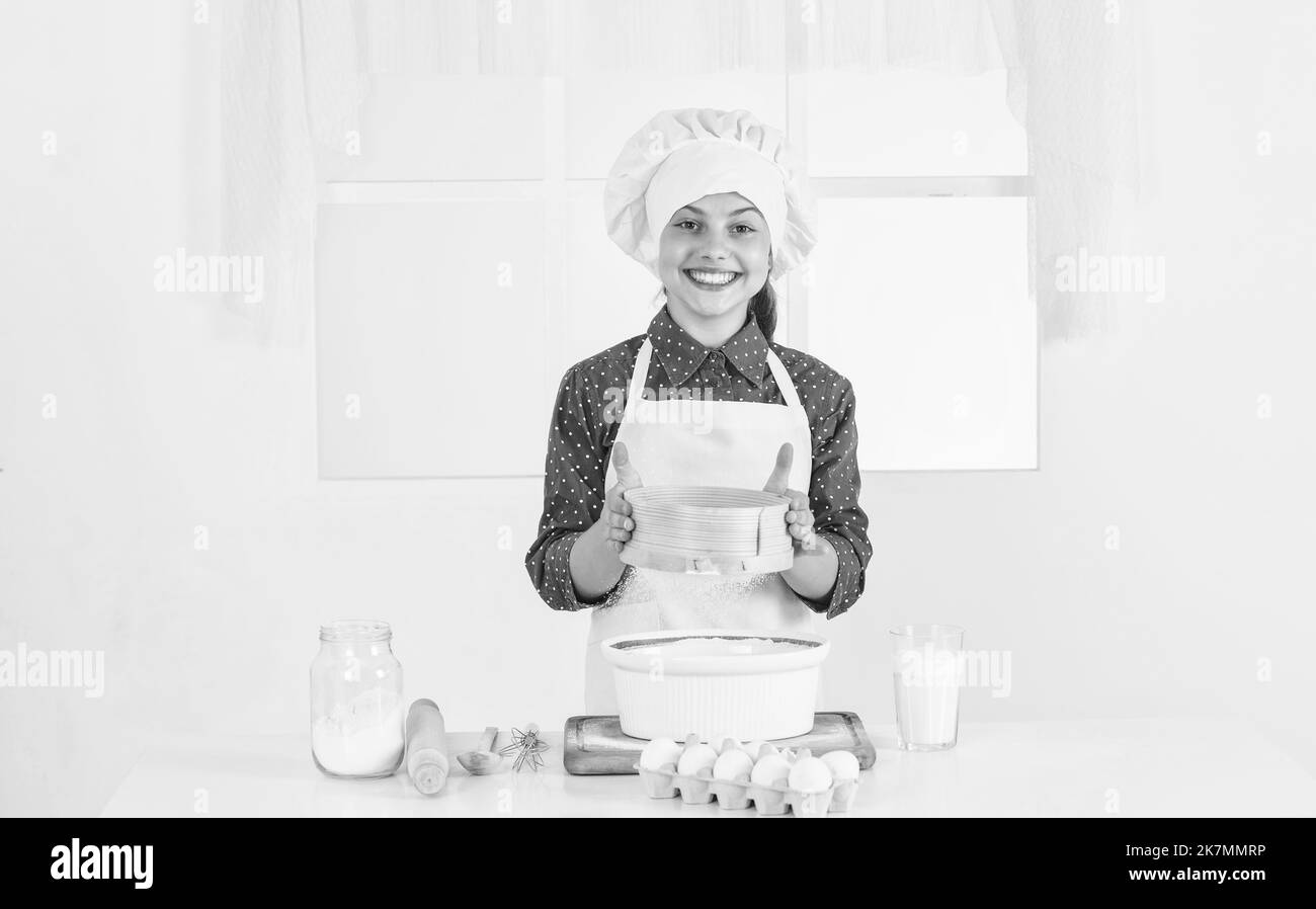 smiling teen girl in chef uniform cooking and baking, cook Stock Photo