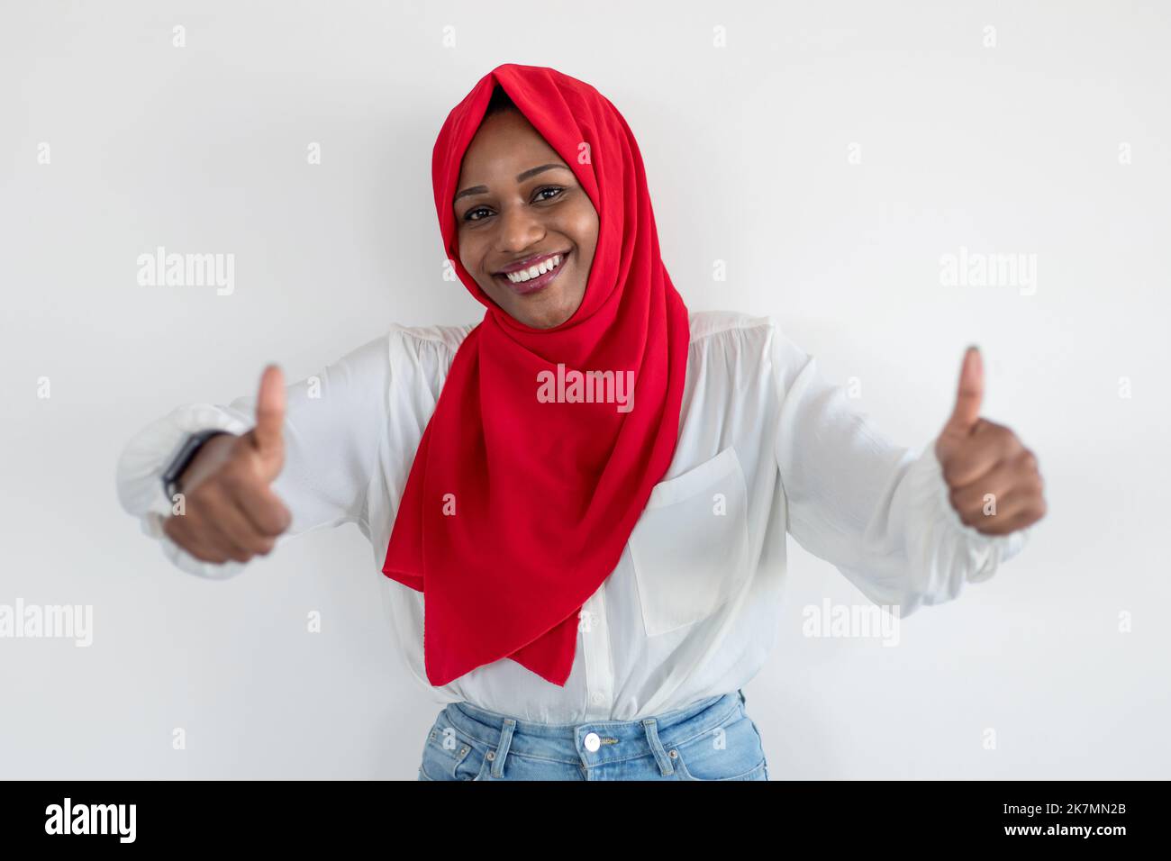 I like and recommend it. Happy black muslim lady in hijab gesturing thumbs up and smiling to camera, white background Stock Photo