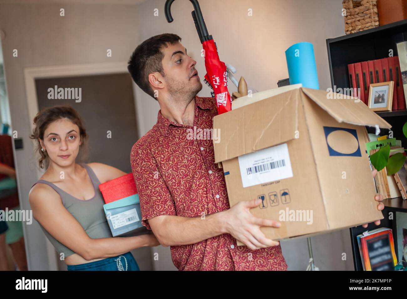 A young couple moves into their new apartment. They are surrounded by ...