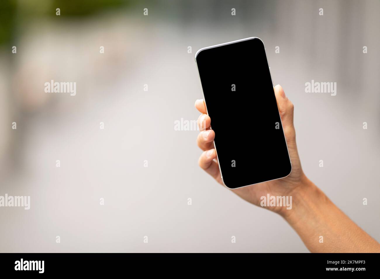 Hand holding modern smartphone with black empty screen, mockup Stock Photo