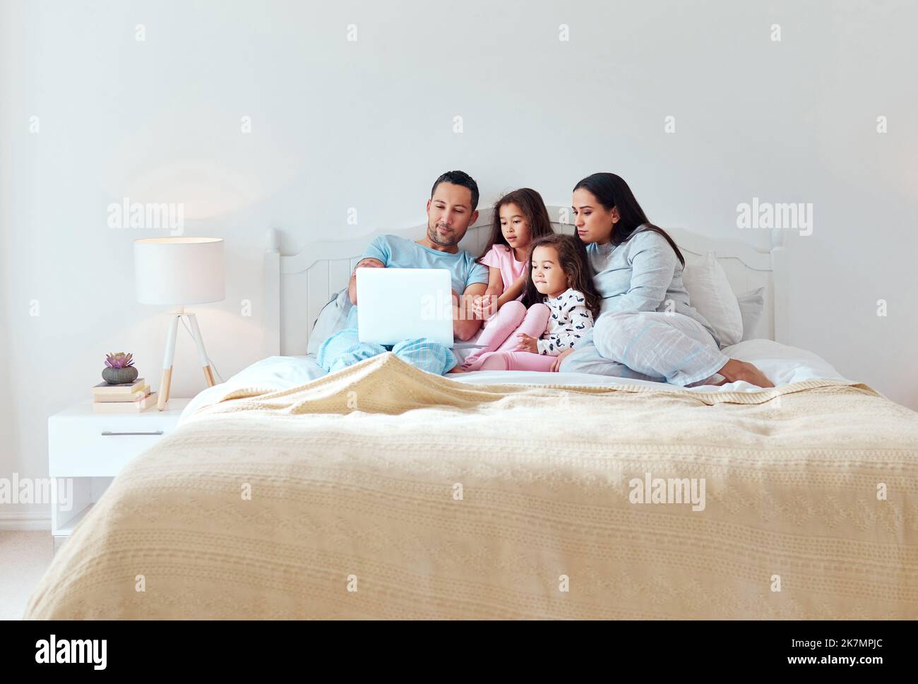 We dont remember everything but well always remember how loved we are. a man using a laptop while sitting with his wife and two daughters. Stock Photo