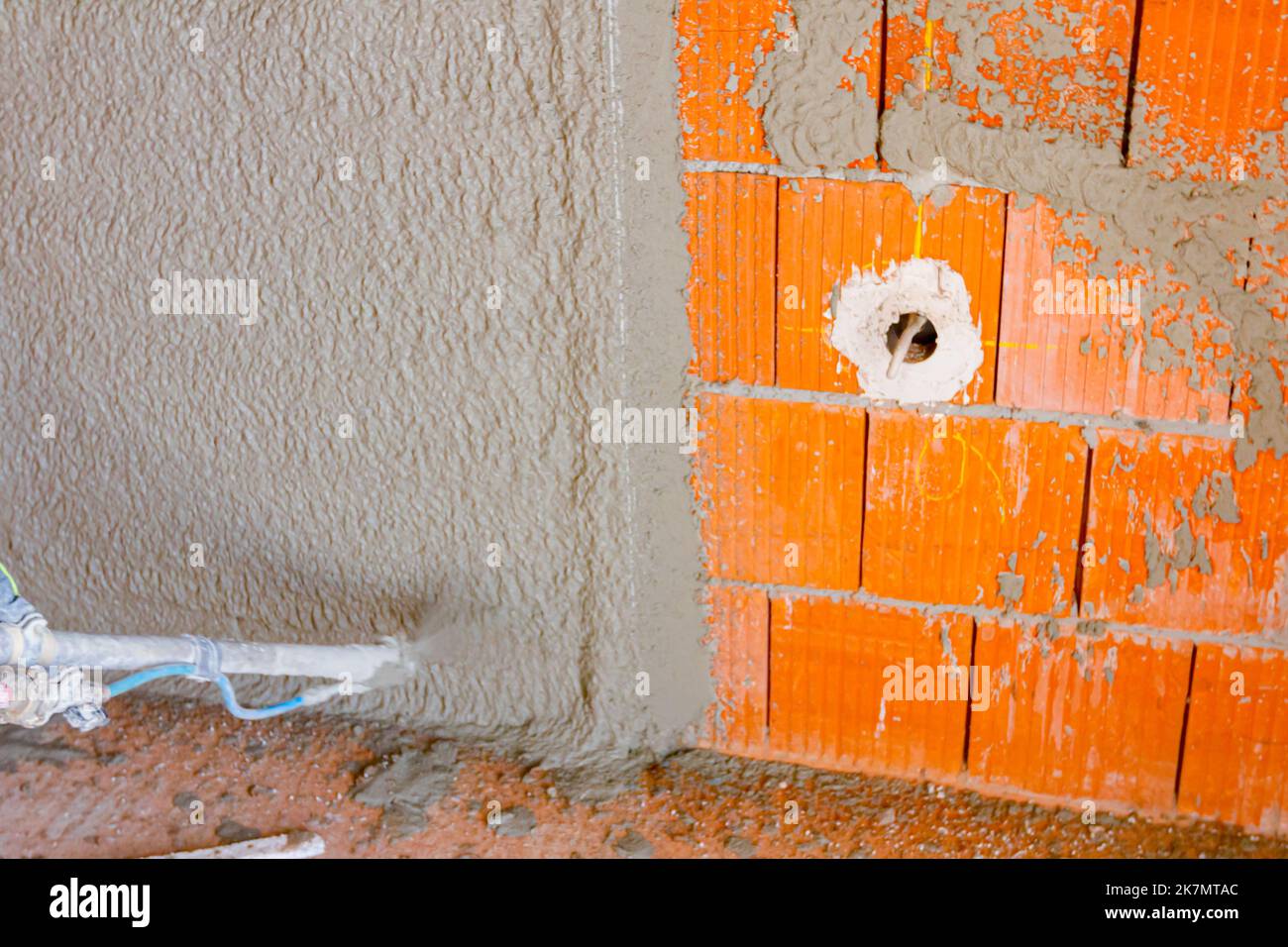 Worker man is holding mortar hose in his hand and plastering under ...