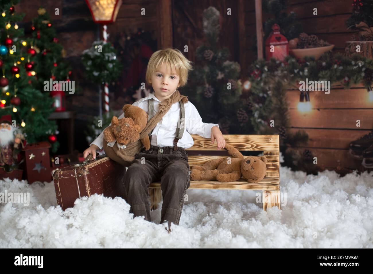 Cute fashion toddler boy, playing in the snow with teddy bear in front ...