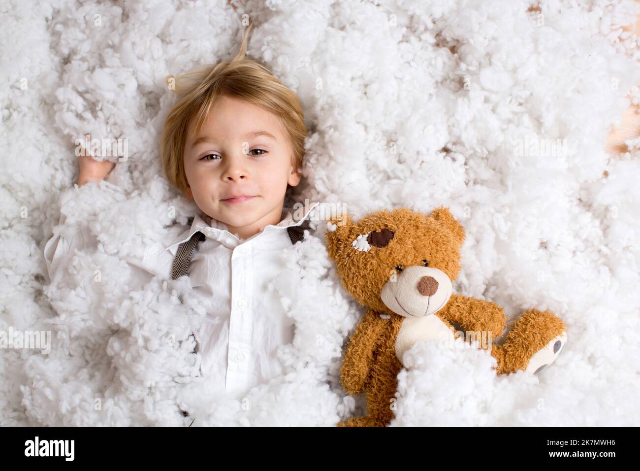 Cute fashion toddler boy, playing in the snow with teddy bear in front ...